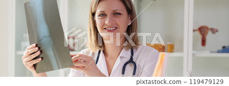 Positive female doctor holds X-ray image of joint of patient 119479129