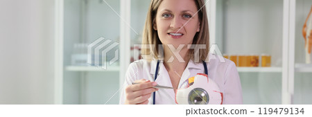 Positive woman points pen to realistic model of eyeball 119479134