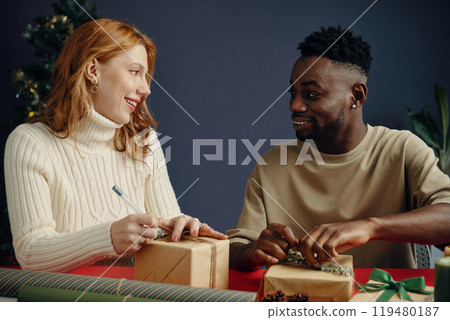 Smiling Couple Wrapping Christmas Gifts Together 119480187