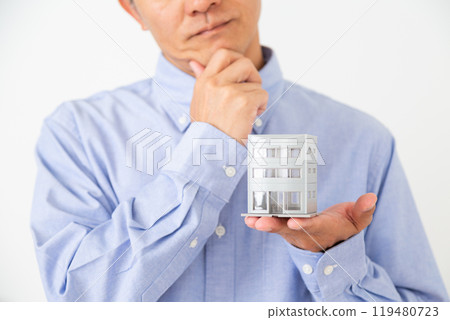 一名中年男子拿著建築模型,憂心忡忡 一名中年男子拿著建築模型,憂心忡忡 119480723