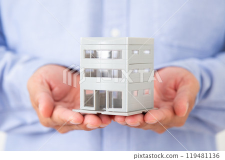 Middle-aged man holding a model of a building 119481136