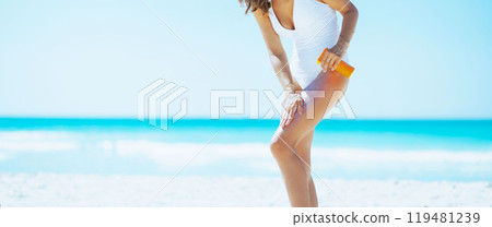Young woman on beach applying sun block creme 119481239