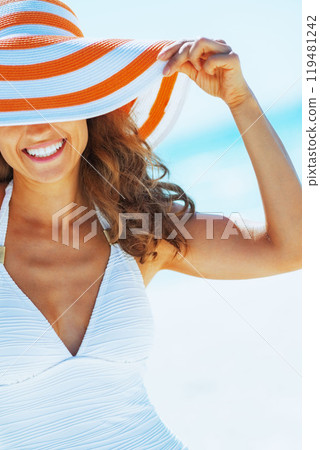 happy young woman in swimsuit hiding behind beach ha happy young woman in swimsuit hiding behind beach ha 119481242