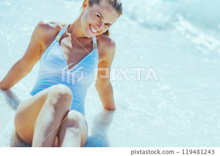 Relaxed young woman sitting at seaside Relaxed young woman sitting at seaside 119481243