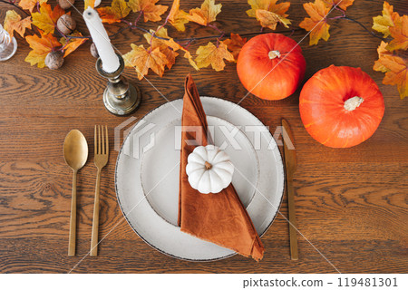 Autumn dinner table setting for holiday with pumpkins, cutlery, and warm fall decorations, top view Autumn dinner table setting for holiday with pumpkins, cutlery, and warm fall decorations, top view 119481301