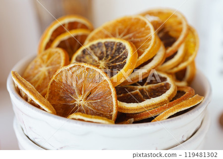 Dried orange slices neatly arranged in a decorative bowl on a bright kitchen counter 119481302
