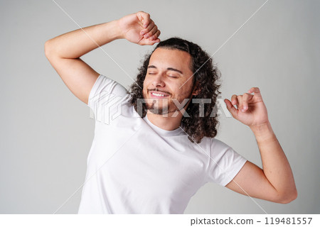 Happy man celebrating success with raised fists in a studio against a plain background Happy man celebrating success with raised fists in a studio against a plain background 119481557