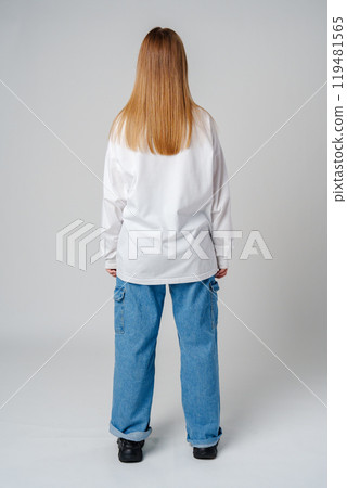 Young adult with long hair standing against a neutral background backwards Young adult with long hair standing against a neutral background backwards 119481565
