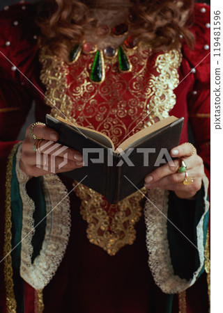 Closeup on medieval queen in red dress with book 119481596