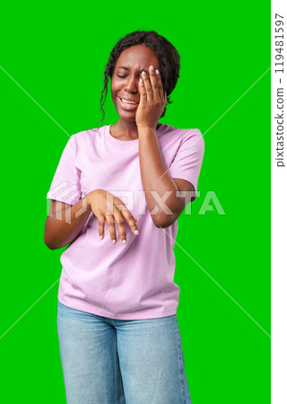 Woman expressing frustration while standing against a bright green background Woman expressing frustration while standing against a bright green background 119481597