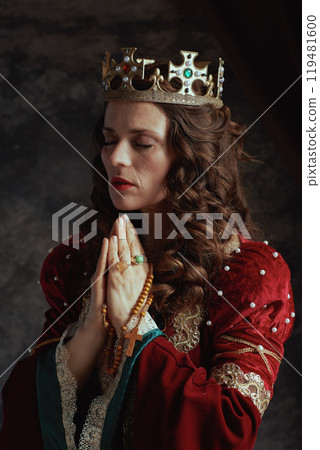 medieval queen in red dress with rosary and crown praying 119481600