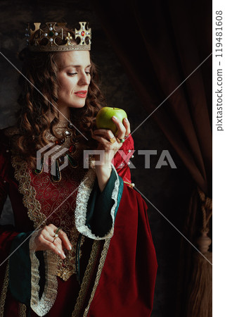 medieval queen in red dress with green apple and crown 119481608