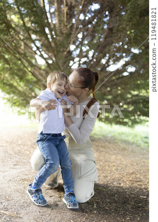 A woman and a child are hugging in a forest 119481821