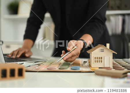 Small house model and color swatches on desk representing architectural design or real estate development 119481886
