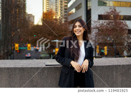 Smiling Canadian businesswoman standing outdoors in bustling downtown area. 119481925