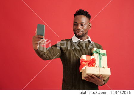 Smiling Man Taking Selfie Holding Gift Boxes Smiling Man Taking Selfie Holding Gift Boxes 119482036