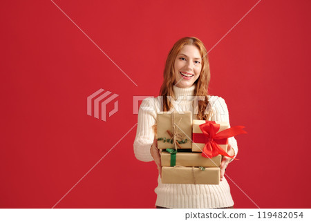 Smiling Woman Holding Gift Boxes on Red Background Smiling Woman Holding Gift Boxes on Red Background 119482054