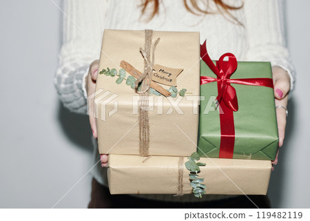 Holding Wrapped Christmas Gifts with Red Ribbon Bow Holding Wrapped Christmas Gifts with Red Ribbon Bow 119482119