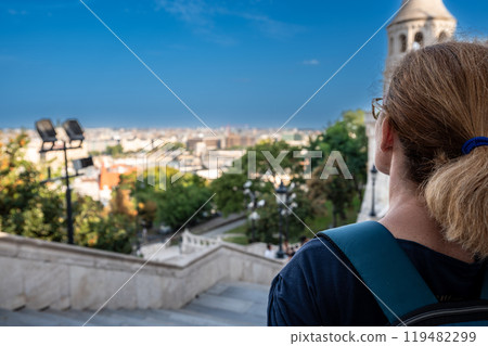 Budapest, Hungary. August 26, 2022. Aerial view of the city overlooking the Danube. A middle-aged woman gazes in fascination at the magnificent landscape. Travel destinations, travel lifestyle. 119482299