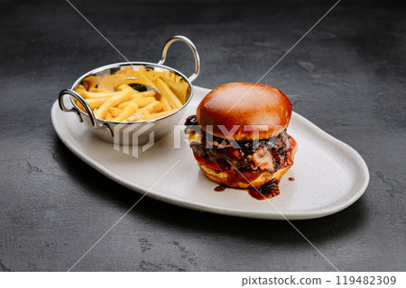 Gourmet BBQ bacon cheeseburger with crispy fries, perfect for indulgent fast food cravings 119482309