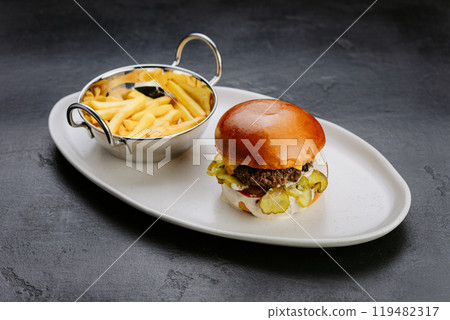 Juicy cheeseburger with pickles, creamy sauce, and soft bun, perfect for a satisfying meal 119482317
