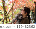 一個女人和她的玩具貴賓犬一起享受秋天的落葉 秋天的風景。 119482362