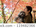 一個女人和她的玩具貴賓犬一起享受秋天的落葉 秋天的風景。 119482366