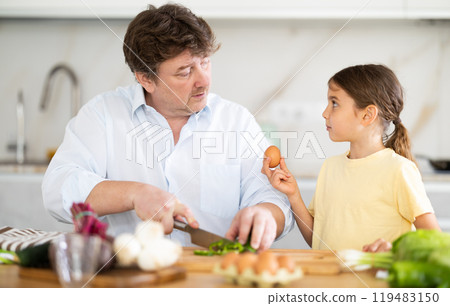 Happy father and daughter share a moment of joy in family kitchen, preparing vegetable salad Happy father and daughter share a moment of joy in family kitchen, preparing vegetable salad 119483150
