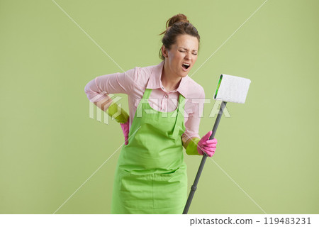 sad woman in green apron and rubber gloves isolated on green 119483231