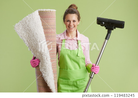 smiling modern housewife vacuum cleaner isolated on green 119483245
