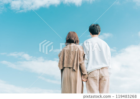 一個男人和一個女人擁抱在一起，看著藍色秋日的後視圖 119483268