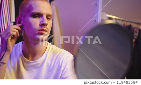 Close-Up: LGBT Individual Trying on Earrings by Large Mirror Close-Up: LGBT Individual Trying on Earrings by Large Mirror 119483584