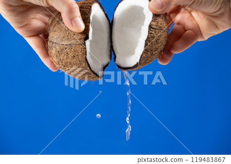 Hands open coconut, coconut water pour out, blue background Hands open coconut, coconut water pour out, blue background 119483867