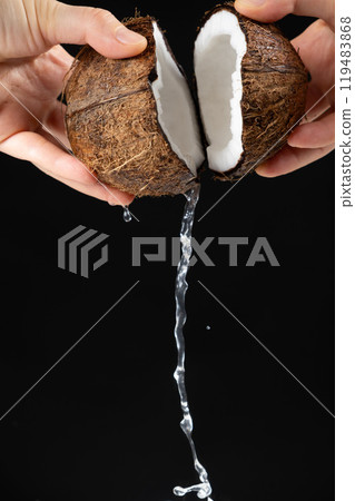 Hands open coconut, coconut water pour out, black background 119483868
