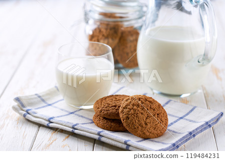 Tasty oatmeal cookies and glass milk on a light kitchen table, selective focus. 119484231