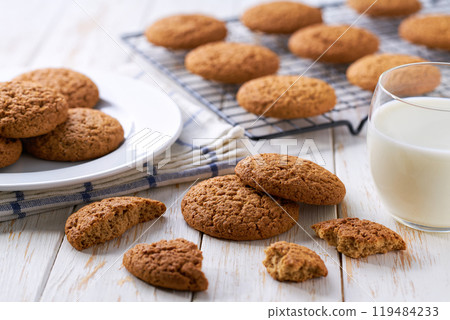 Low-calories oatmeal cookies and glass milk on a white table. 119484233