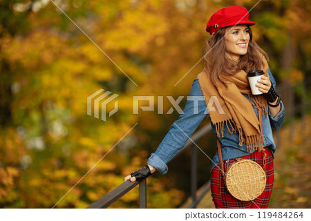 smiling young woman in jeans shirt and red hat with scarf 119484264