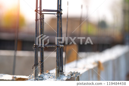 Concrete footings and reinforcing steel rods at a construction site. Groundwork for new building foundation. Reinforcement steelwork providing strength and stability for long term structural integrity Concrete footings and reinforcing steel rods at a construction site. Groundwork for new building foundation. Reinforcement steelwork providing strength and stability for long term structural integrity 119484438