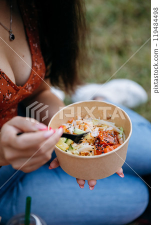 Eating poke bowl outdoors during picnic, capturing vibrant, healthy meal with fresh ingredients Eating poke bowl outdoors during picnic, capturing vibrant, healthy meal with fresh ingredients 119484498