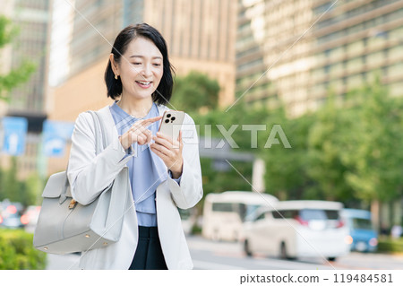 在辦公區操作智慧型手機的女商人 在辦公區操作智慧型手機的女商人 119484581