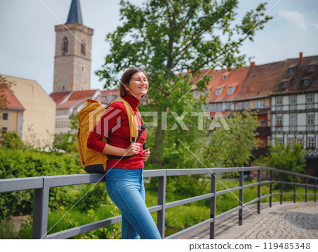 Tourist woman explores beautiful city of Erfurt, wandering through its historic streets, admiring charming architecture, and discovering cultural landmarks, fully immersed in citys rich heritage. 119485348
