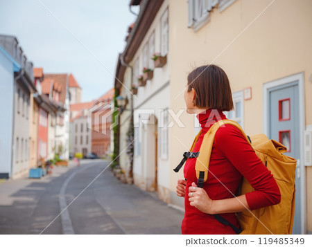 Tourist woman explores beautiful city of Erfurt, wandering through its historic streets, admiring charming architecture, and discovering cultural landmarks, fully immersed in citys rich heritage. Tourist woman explores beautiful city of Erfurt, wandering through its historic streets, admiring charming architecture, and discovering cultural landmarks, fully immersed in citys rich heritage. 119485349