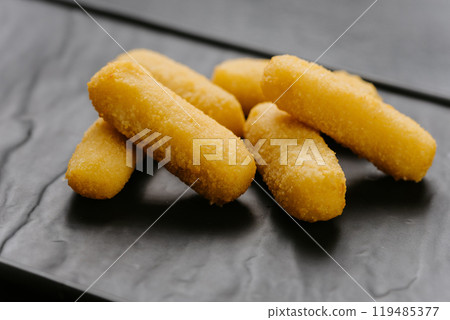 Crispy cheese sticks served on a black plate, perfect snack or appetizer for any occasion Crispy cheese sticks served on a black plate, perfect snack or appetizer for any occasion 119485377