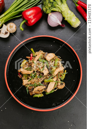 Stir-fried chicken with vegetables and glass noodles, garnished with sesame seeds for a healthy meal 119485378