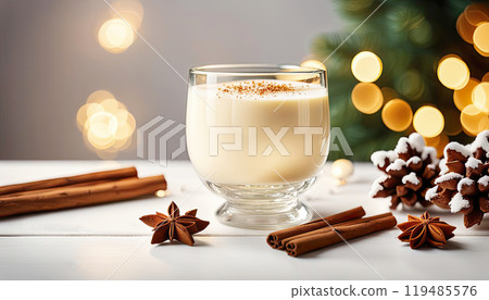 Christmas drink with cinnamon sticks and anise stars, glass of sweet classic eggnog cocktail decorated background with fir tree and baubles 119485576