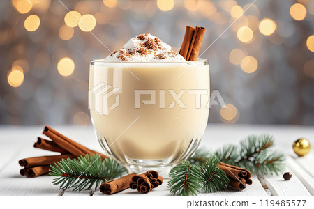 Christmas drink with cinnamon sticks and anise stars, glass of sweet classic eggnog cocktail decorated background with fir tree and baubles 119485577