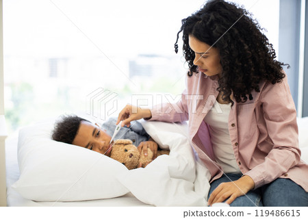 Mother caring for sick child with thermometer at home 119486615