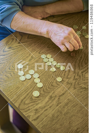 senior female sitting miserably at the table at home and counting coins. High quality photo senior female sitting miserably at the table at home and counting coins. High quality photo 119486868