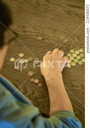 senior female sitting miserably at the table at home and counting coins. High quality photo 119486872