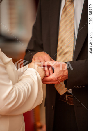 A warm wedding ceremony with hand holding, symbolizing love and commitment, surrounded by family A warm wedding ceremony with hand holding, symbolizing love and commitment, surrounded by family 119486930